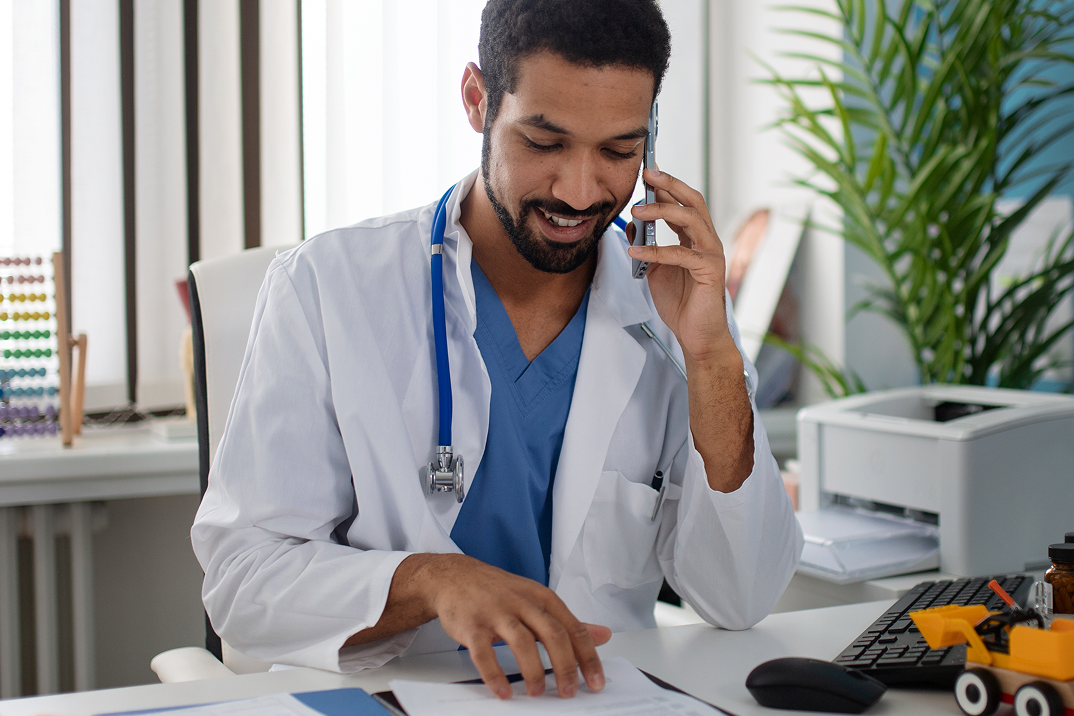 Doctor talking on phone while reviewing medical documents in clinic